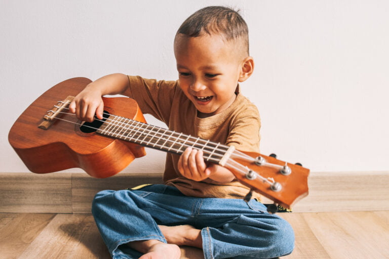 menino pequeno com um violão (música) pequeno e sorrindo